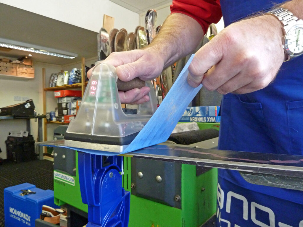 An iron gliding over skis which is ironing in wax