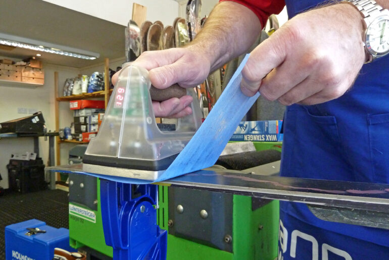 An iron gliding over skis which is ironing in wax